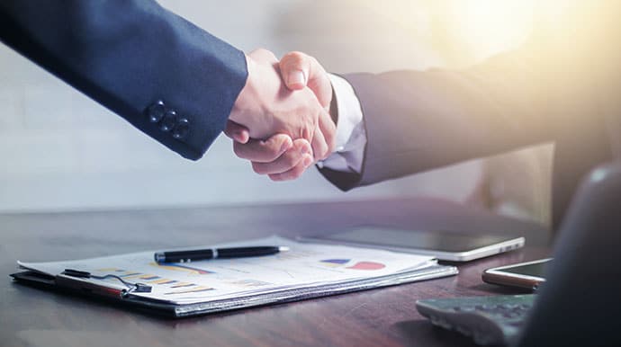 Two businessmen shaking hands after crafting agreements for independent contractors
